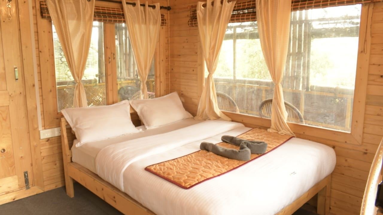 Wood-panelled room with a double bed, white linen and curtained windows