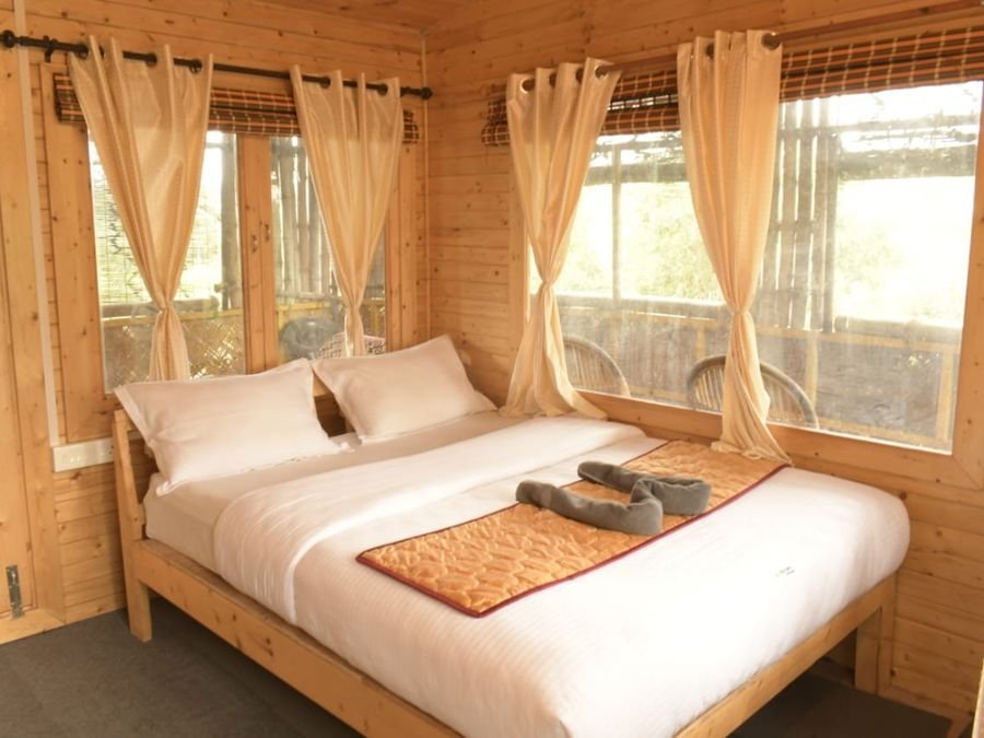 Wood-panelled room with a double bed, white linen and curtained windows